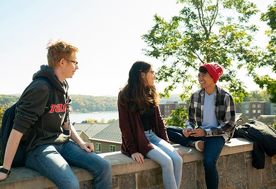 An image of students sitting on a ledge.